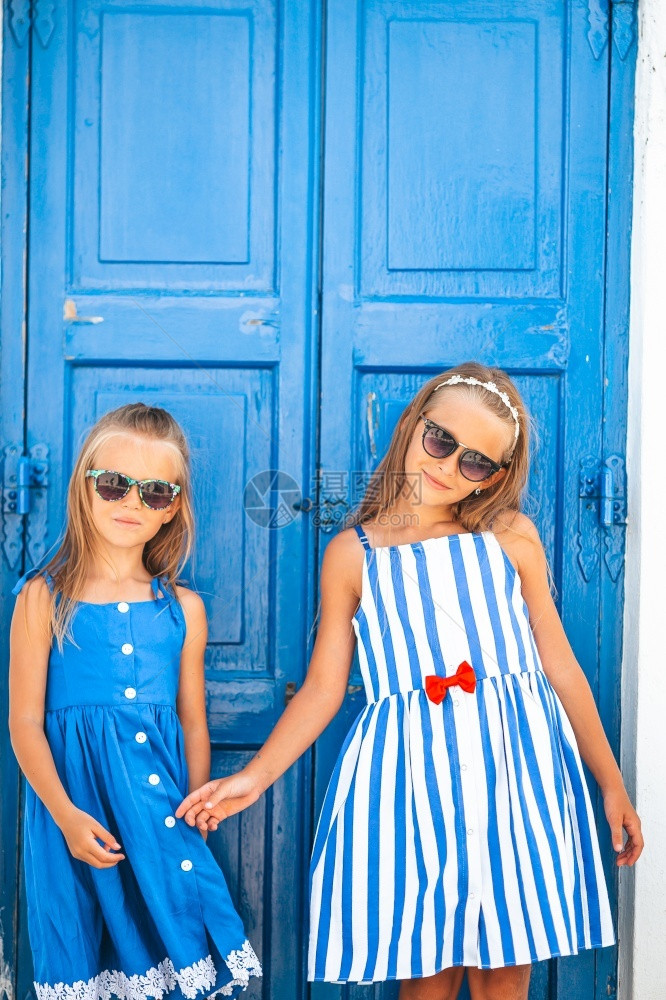 米科诺斯岛快乐的小姑娘们在街上玩得开心在希腊密科诺斯岛典型的希腊传统村庄穿着服装的小女孩们也很开心仙人掌太阳镜屋顶图片