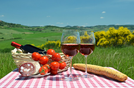 农业村庄谷红酒面包和番茄在彩布上与意大利的托斯卡纳风景对抗图片
