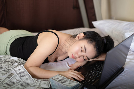 穿着笔记本和10美元钞票睡在卧室的床上亚洲年轻有魅力的肖像女青年很多是自家作品卖商以牟利概念SellProjectsfor盈利概年轻的高清图片素材