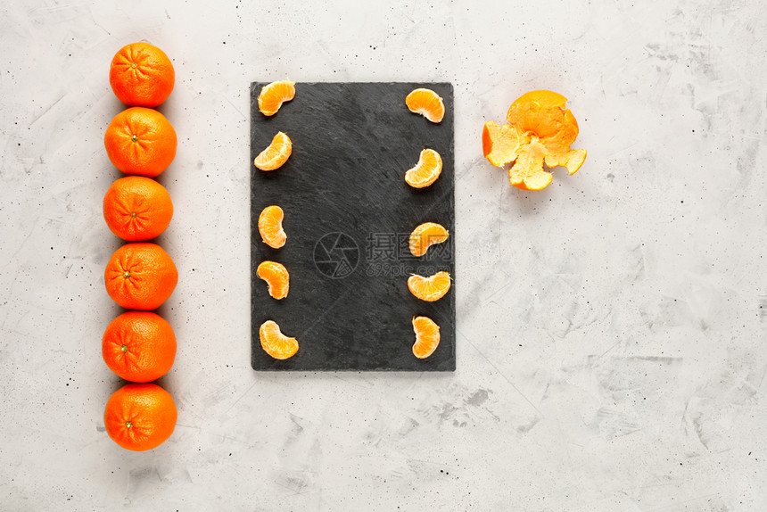异国情调橘子亮光和多汁的碎片躺在灰色板块上旁边是一排甚至连的整串橙黄色橘子位于灰混凝土背景上复制空间布林特和多汁的剥皮曼达林片落图片