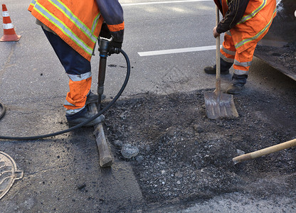 a道路维修服务人员大队清除旧沥青在道路建设中用1个打火机和铲子把旧沥青搬进挖土车推工兵夸克大队在道路建设中用铲子清理部分沥青建造图片