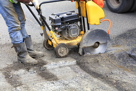 街道路施工消除技术员在修理公路时启动汽油钻石发机以清除旧沥青工人开始使用汽油切割机的发动以便切断和清除公路上的坏沥青b修车团队高清图片素材