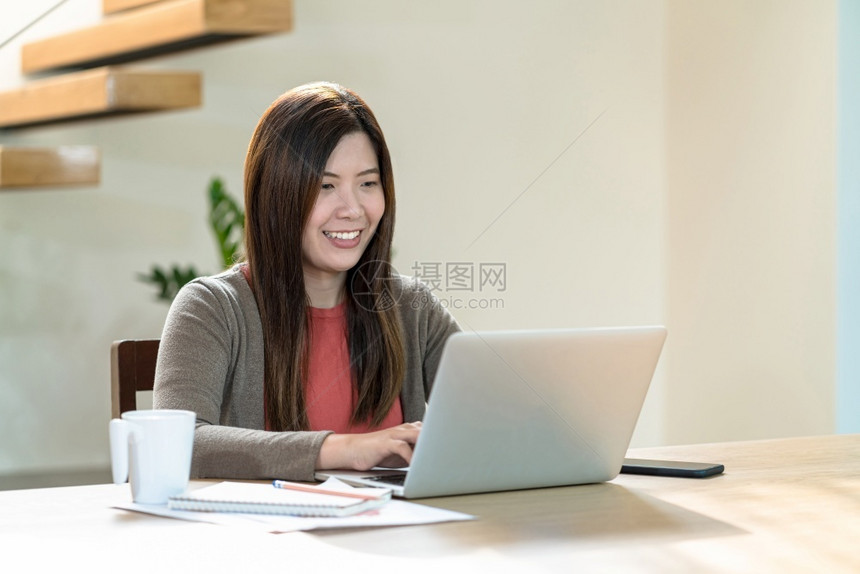 桌子工作场所亚洲商业妇女使用技术笔记本电脑和移动话在家工作室内现代住宅自由职业者和企家创者和和企主社会距离和自我责任中从事家庭工图片