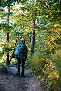 草真正的在暑假旅行期间带着背包走在穿过森林的道路上走过森林的青年妇女徒步旅行者放松高清图片素材