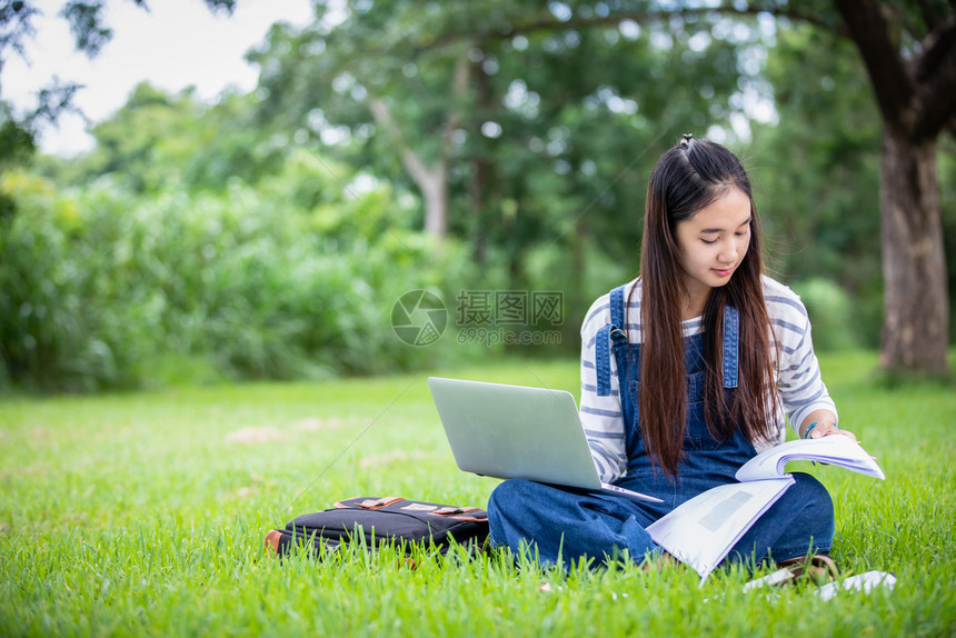 坐在草地上使用笔记本电脑的女孩图片