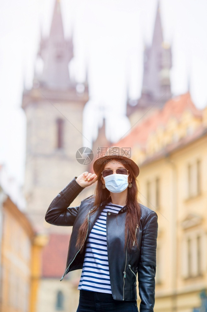 旅游捷克布拉格著名桥上欧洲城市戴口罩预防的快乐年轻女白种人游客沿着欧洲空荡的街道行走在欧洲城市捷克布拉格著名桥上的欧洲城市快乐年图片