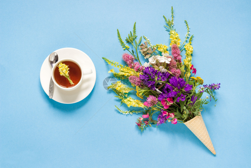 华夫饼冰淇淋锥花朵和蓝绿松石背景的草药茶上午好夏日茶晚会欢呼卡片平板套餐空间花朵华夫饼冰淇淋果和茶杯中的花朵子平坦粉彩图片