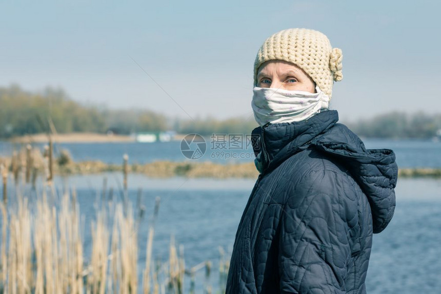 贫穷的老年妇女佩戴自制面罩保护己免受诸如冠状又称covid19或SARS和MERS等之害她坐在河边的长椅上医疗oopicapi卫图片