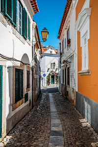 卡斯卡伊斯入口葡萄牙卡斯伊老城粉刷房屋和墙壁之间的狭窄鹅卵石小巷街道葡萄牙卡斯伊老城粉刷房屋和墙壁之间的狭窄鹅卵石小巷街道老的正面背景