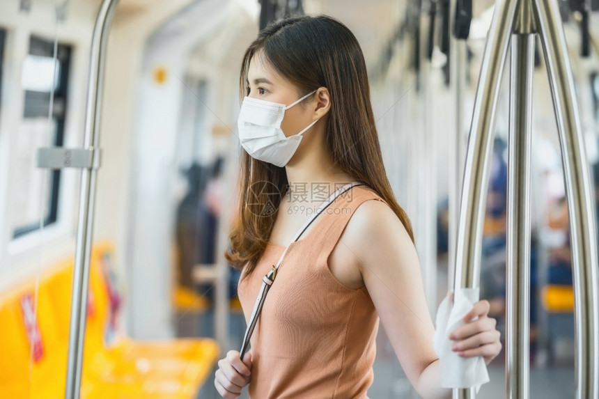 什么时候在Covid19爆发感染和大流行病等新常识概念的大城市旅行时身戴外科面具并在地铁火车上手触湿擦巾的亚洲女青年乘客轻的人们图片