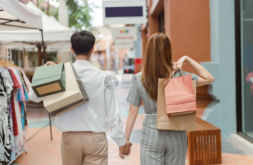 零售男纸女店商在走过服装时手牵背着购物袋每部携带东西袋男女商店家图片