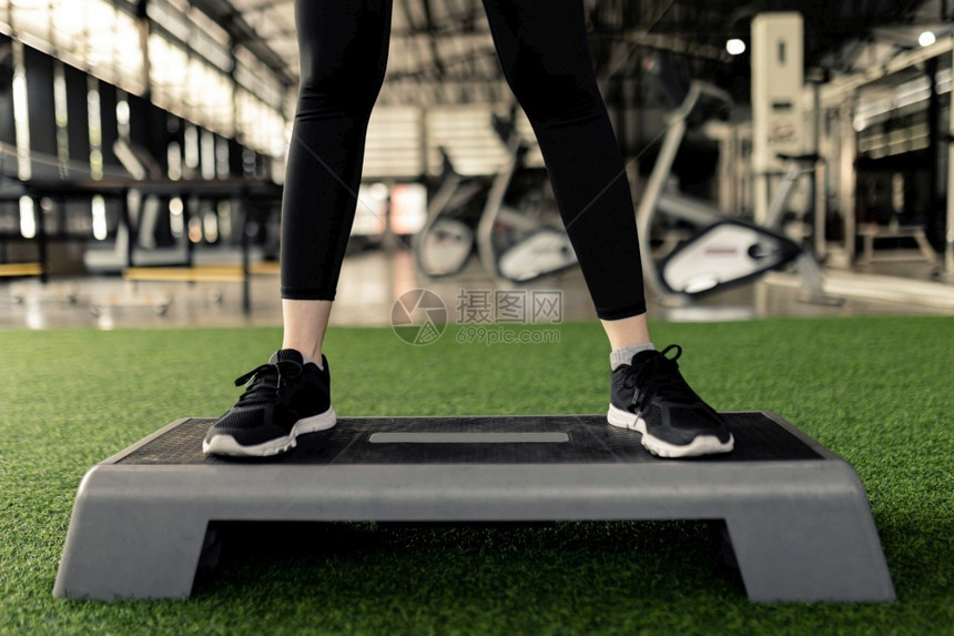 重量女运动者用脚站起蹲比宽度大一点在灰色平台前对面的脚趾尖正在做深蹲图片
