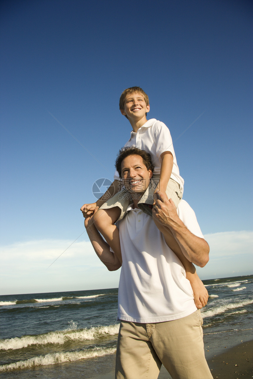 爸爸的肩膀上带着儿子中年人假期男孩父亲海滩家庭孩子男子男人支撑图片