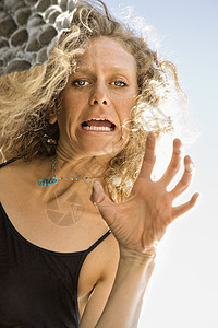女人做脸手势岩石倾斜低角度女性中年头发金发中年人金发女郎背景图片