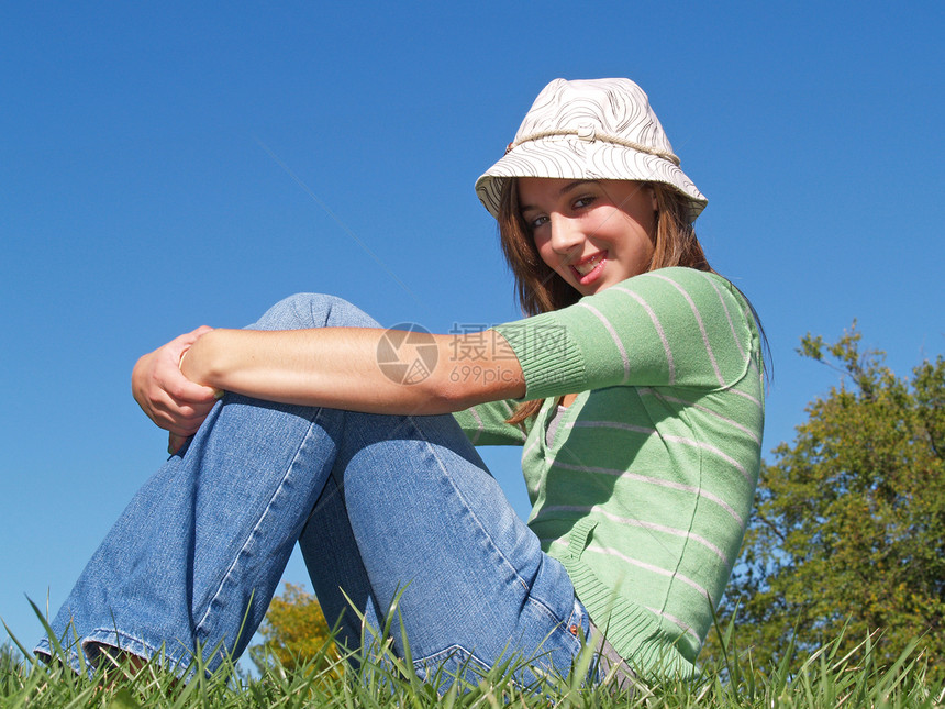 坐在草地上的少女青春期天空女性帽子成人太阳女士幸福女孩图片