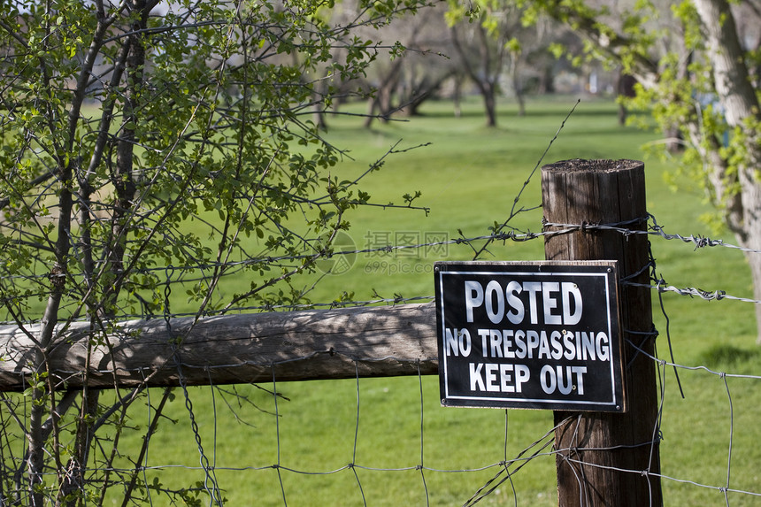绿色高尔夫球场周围的围栏上没有非法闯入标志图片