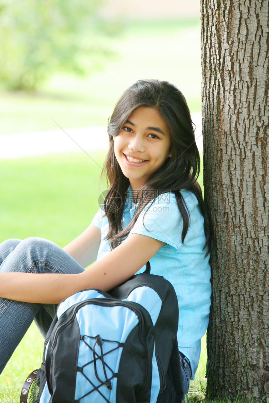 年轻女孩坐在树边 背着背包草地公园中学青少年孩子微笑混血学生图片