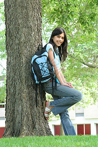 年轻的少女站在背着背包的树上混血精力中学学生女孩孩子青少年晴天背景图片