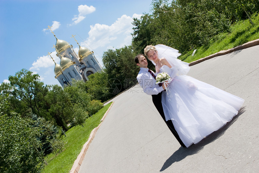 一个快乐的新娘 和教堂附近的新郎图片