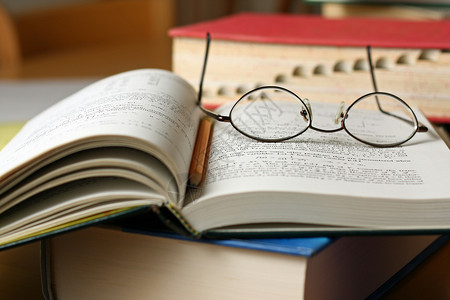 带眼镜和铅笔的放在桌上的教科书背景图片