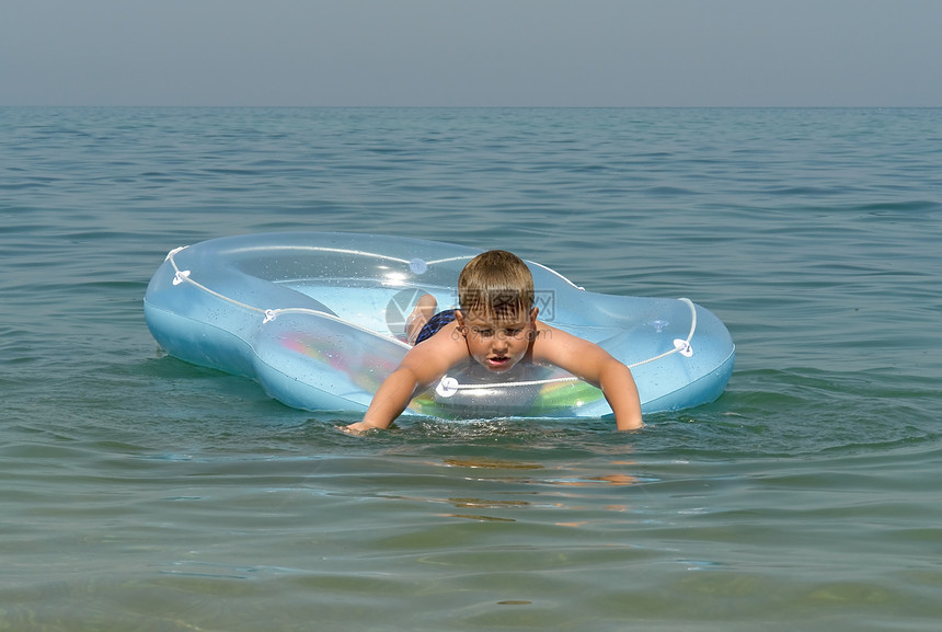 男孩在一条充气船上孩子们假期男性男孩们男人蓝色童年孩子自由太阳图片