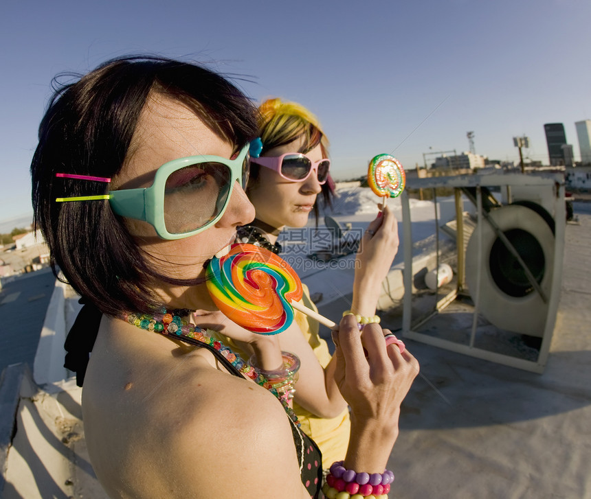 屋顶上有棒棒棒糖的有趣的女孩鱼眼女性塑料糖果玩具微笑牙齿型号头发太阳镜图片