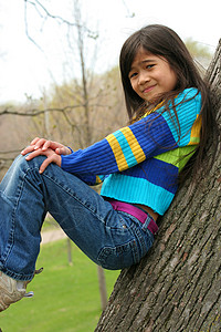 坐在树上可爱的小女孩福利孩子女性混血精力微笑牛仔裤倾斜背景图片