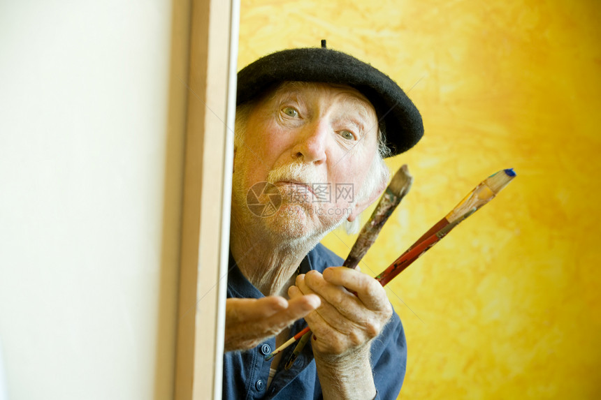 艺术家与贝雷帽在坎瓦斯看模型思考创造力刷子插画家画家灰色皱纹沉思男人老年图片