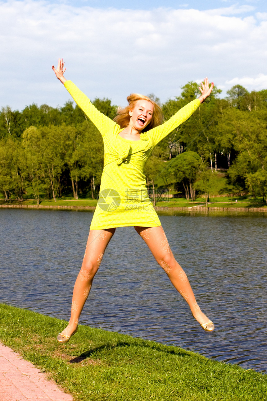 快乐的姑娘跳到河岸上女孩微笑身体成人女士天空运动闲暇运动员女性图片