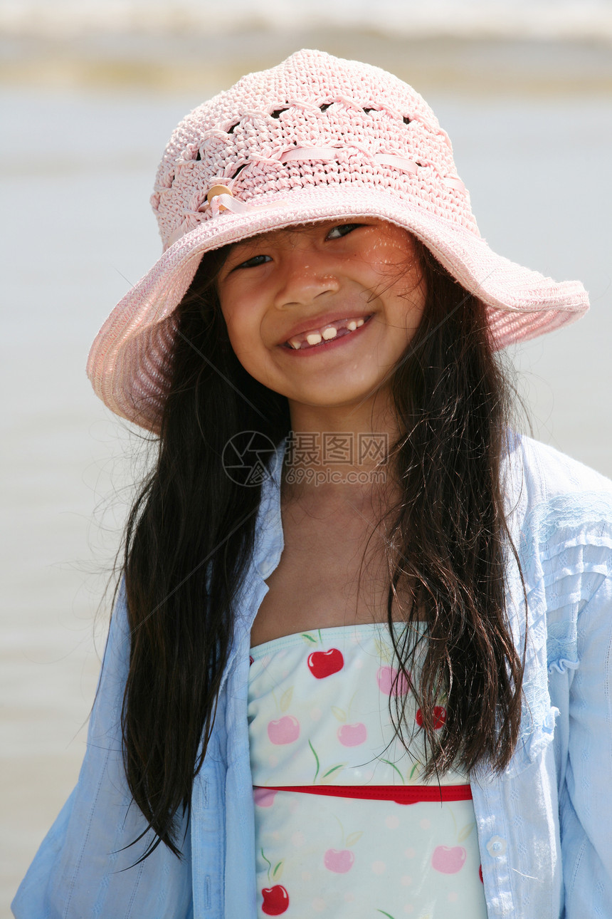 海滩上可爱的小女孩混血儿晴天牙齿女孩海洋帽子乐趣海滨泳装享受图片