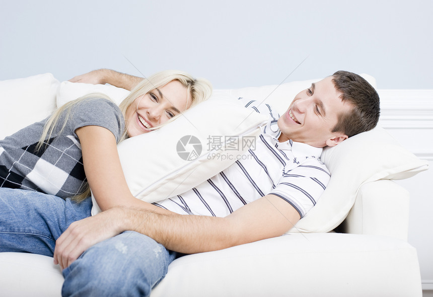 年轻夫妇在索法的坐靠幸福金发成人衬衫头发条纹房子女性蓝墙沙发图片