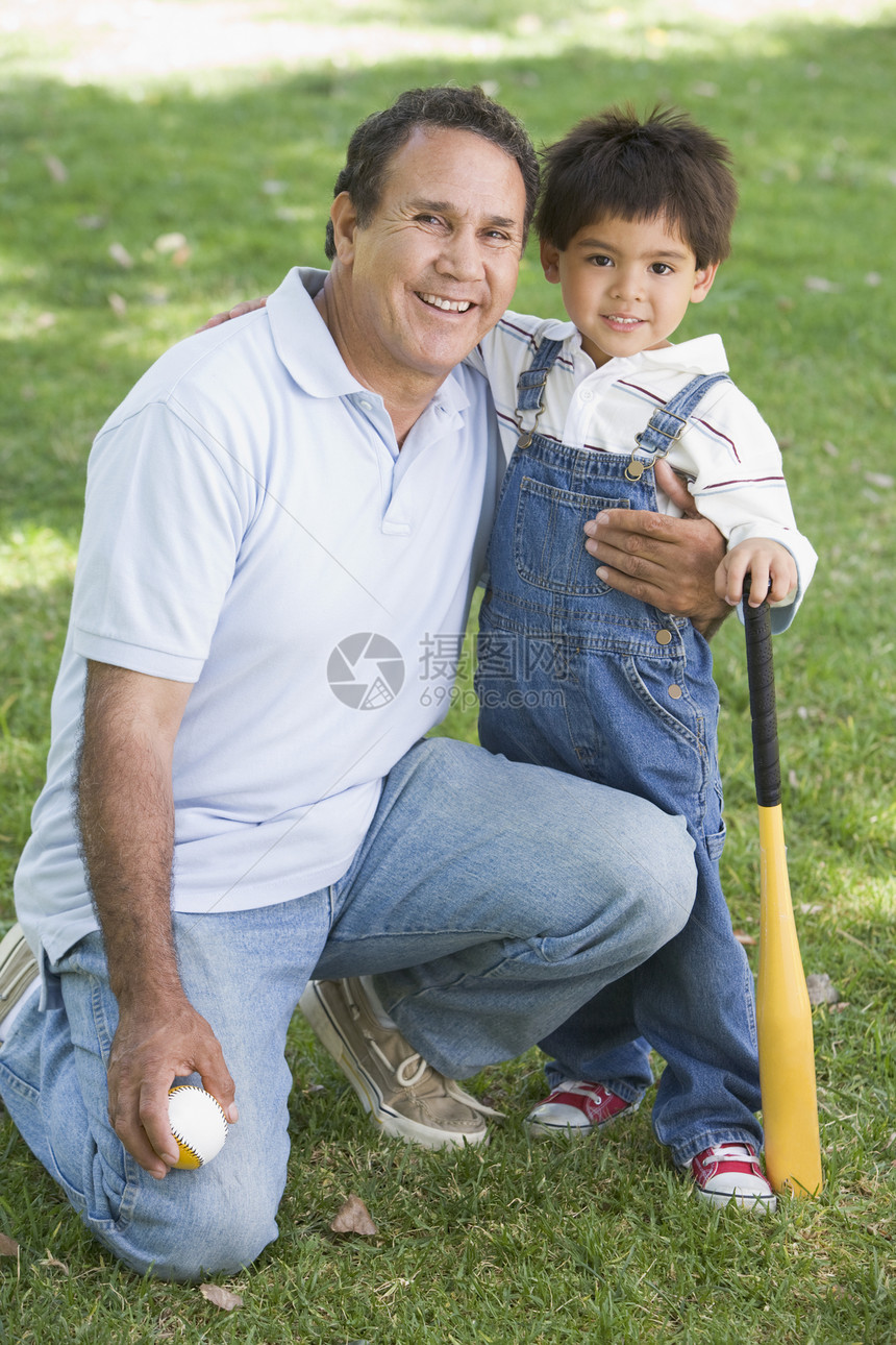 拿着棒球棒和微笑的祖父和孙子图片
