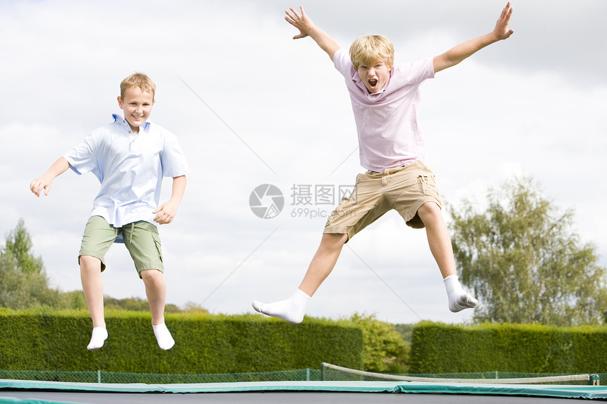 两个男孩在蹦床上笑着跳跃图片