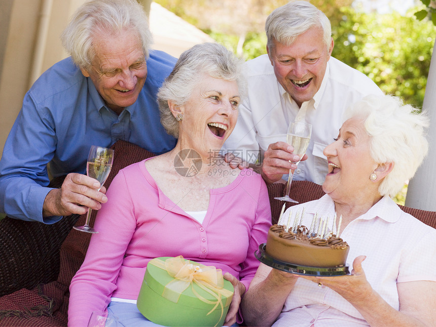 两对在院子上的情侣 带着蛋糕和礼物微笑退休四个人乐趣老年男人友谊蜡烛香槟酒精惊喜图片