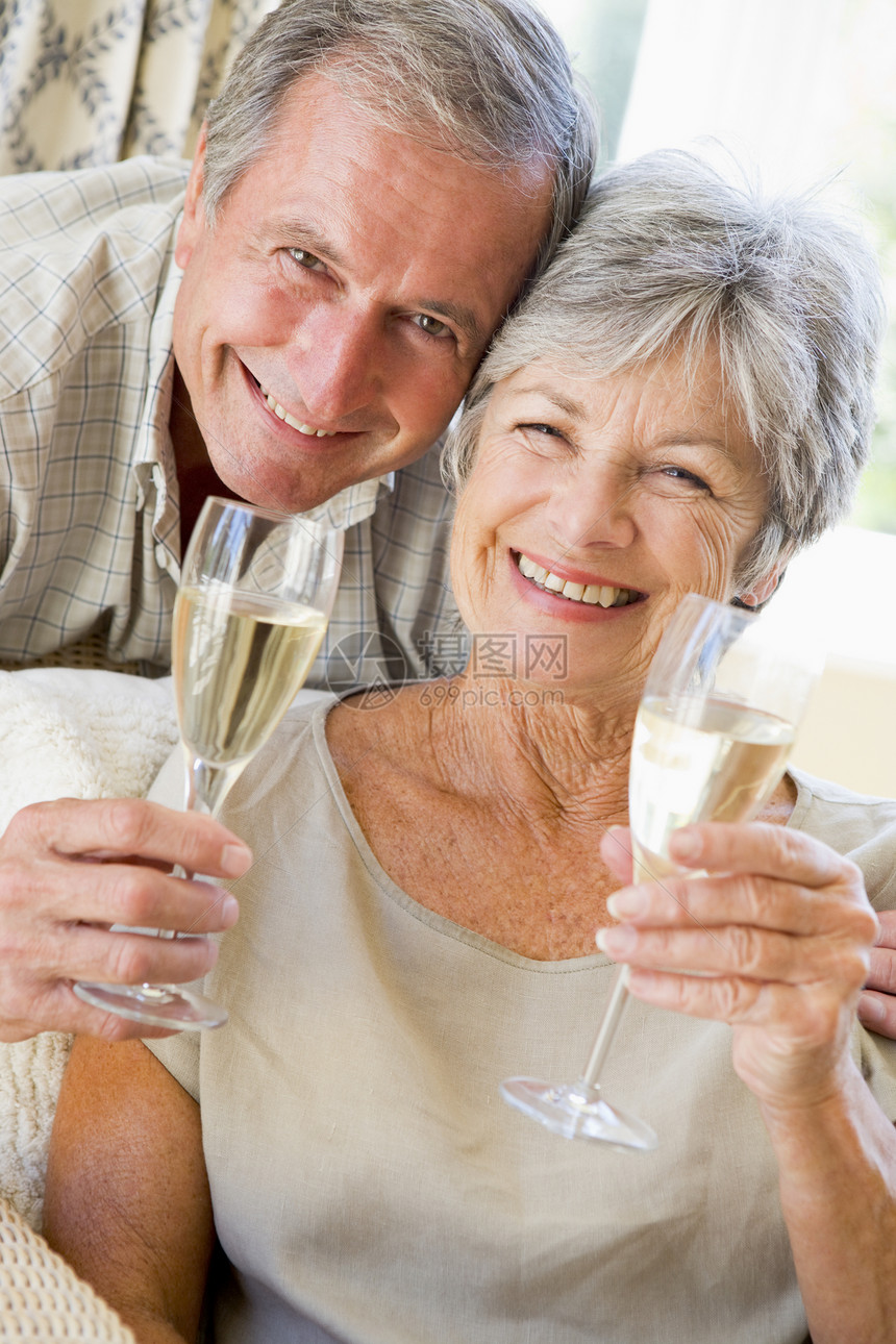 在客厅的一对夫妇 喝香槟和微笑图片