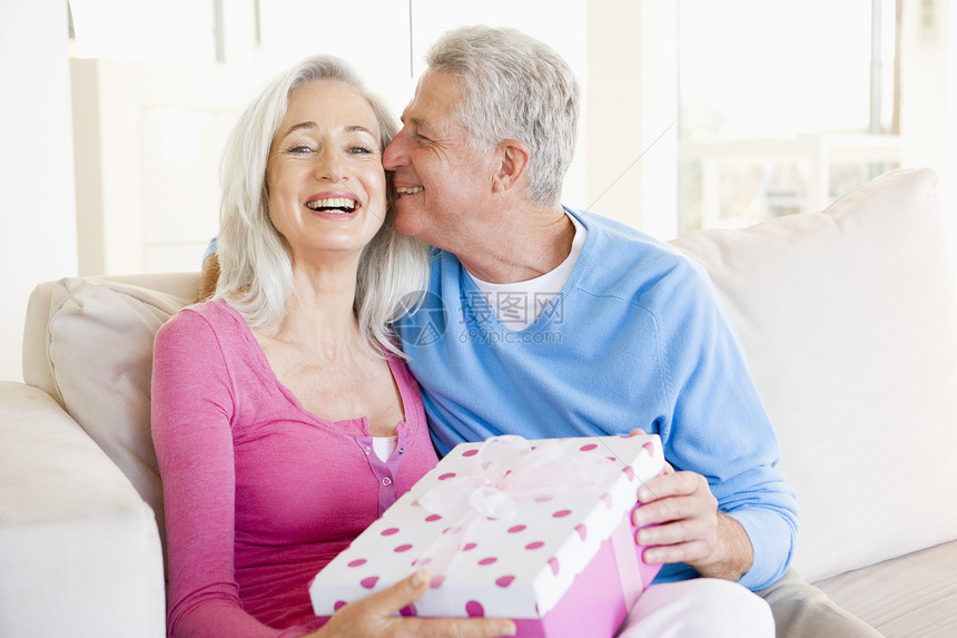 丈夫在客厅里赠送妻子礼物 亲吻她并微笑展示感情生日男人沙发女性夫妻盒子伙伴女士图片