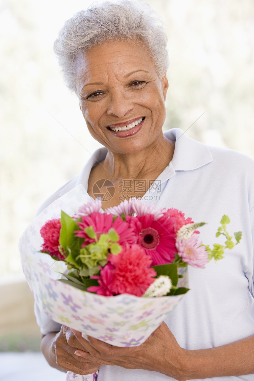 妇女拿着鲜花和微笑纪念日退休花束生日亲热礼物相机情感周年场合图片