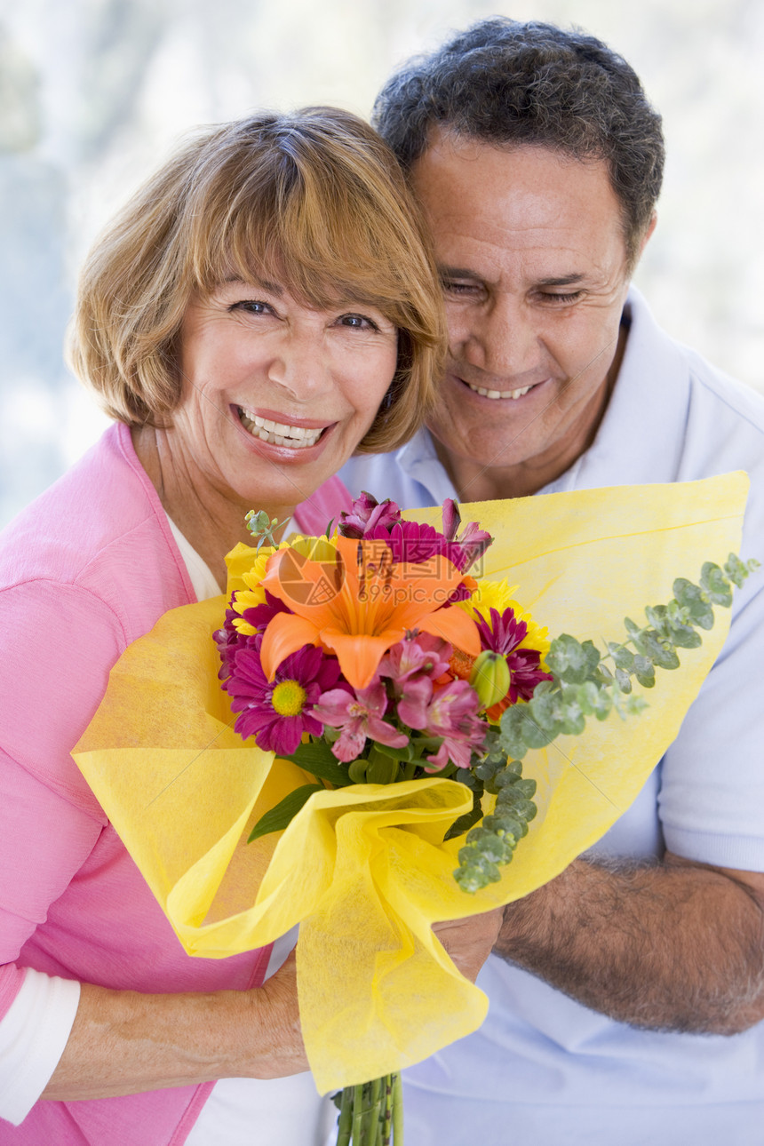 丈夫和妻子拿着鲜花 微笑着笑容情感花朵伙伴周年浪漫展示亲热女性男人女士图片
