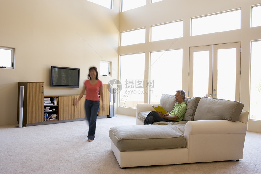 男人在客厅看书 女人走过运动女士电视丈夫男性音响两个人房间家庭伙伴图片