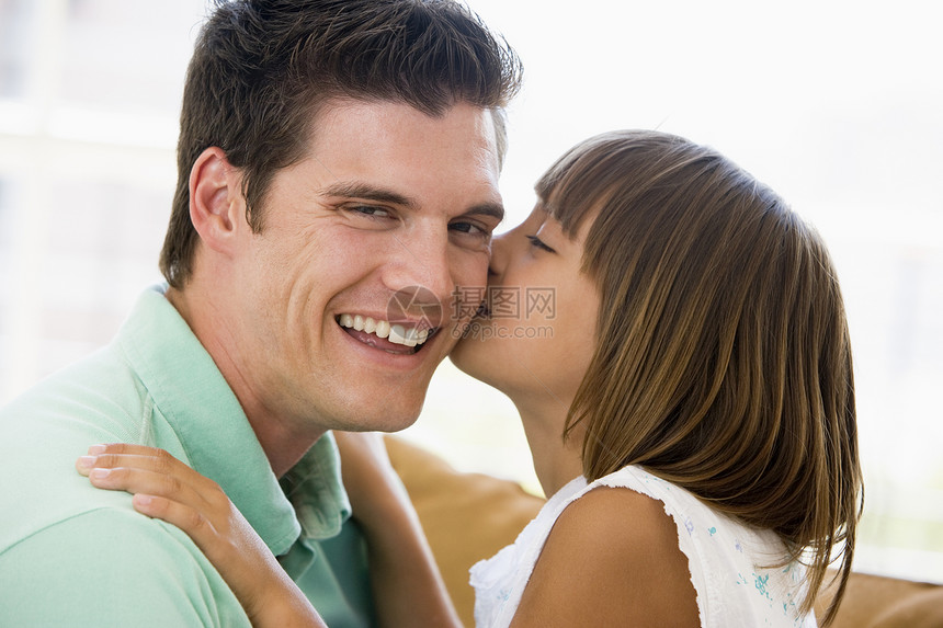 年轻女孩在客厅里亲吻微笑的男人图片