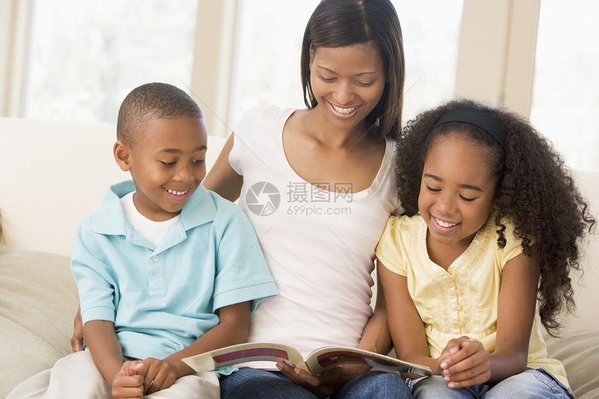 妇女和两名儿童坐在起居室阅读书上故事休息室家庭生活家庭沙发客厅孩子亲热感情女孩图片