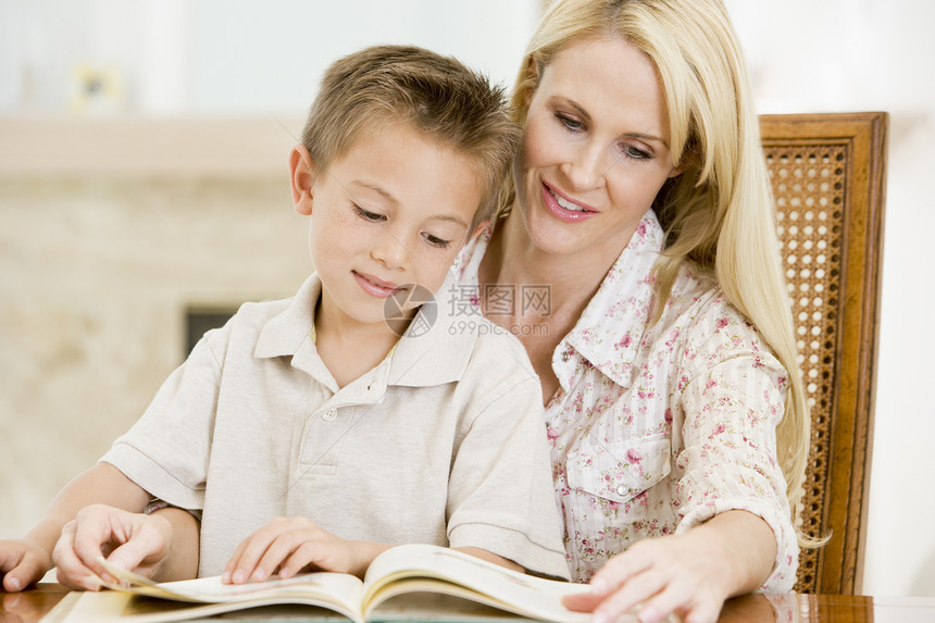餐厅里的女人和年轻男孩微笑着看书休息室阅读男性故事女士家长女孩小男孩客厅家庭图片