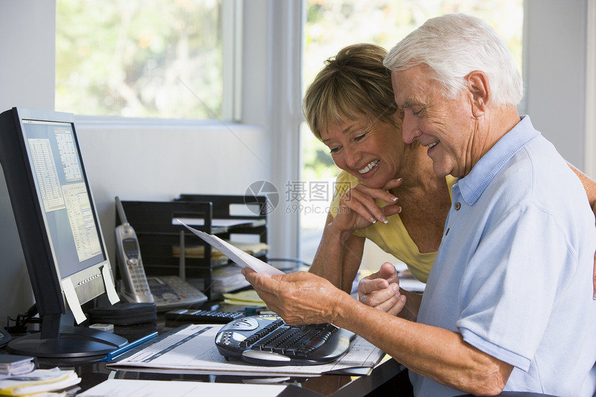 家庭办公室的情侣 带着电脑和文件微笑两个人阅读夫妻文档水平女士技术帐单工作站成人图片