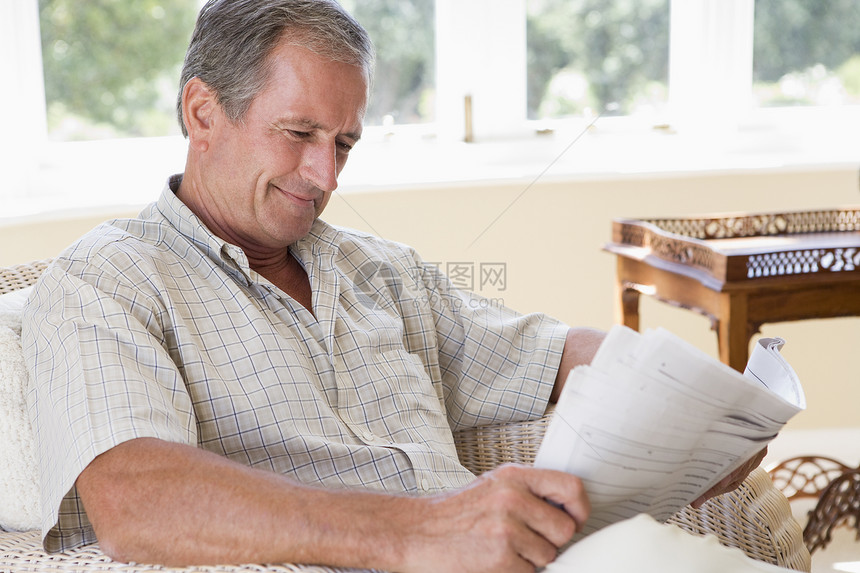男人在客厅看报纸笑着看报纸阅读微笑椅子水平长椅男性相机休息室长度沙发图片