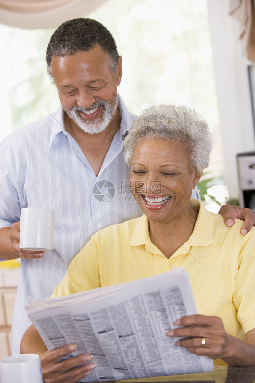 一对夫妇在报纸上笑着放松丈夫两个人退休妻子厨房女性咖啡微笑阅读一杯茶图片