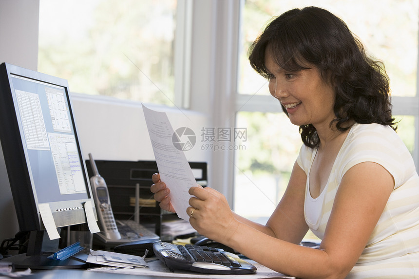 在家办公室工作的妇女 带着计算机和文件的微笑婴儿中年女性技术账单文书工作站成人阅读女士图片