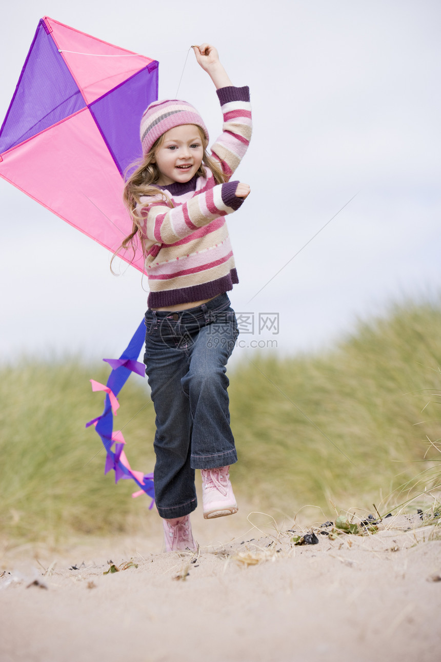 海滩上年轻女孩带着风筝微笑图片
