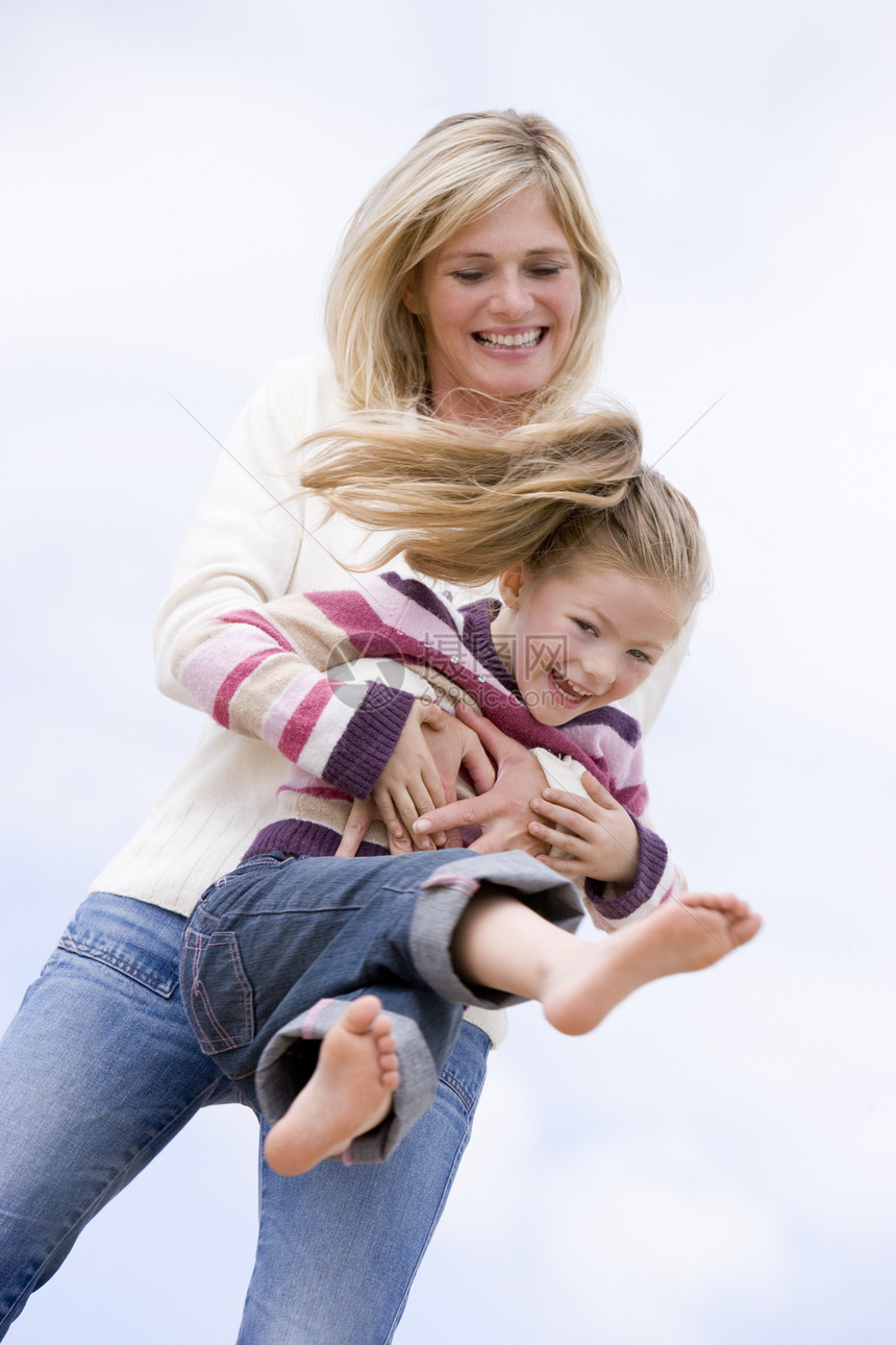 母亲和女儿在海滩上笑着玩图片