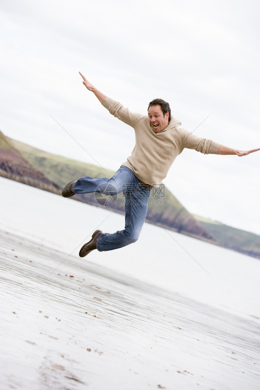 男人在海滩上欢笑的跳跃图片