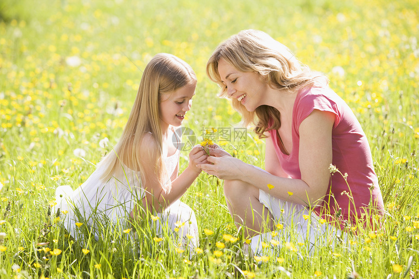 母亲和女儿在户外微笑着花朵的鲜花女性妈妈公园享受毛茛中年女士采摘农村季节图片